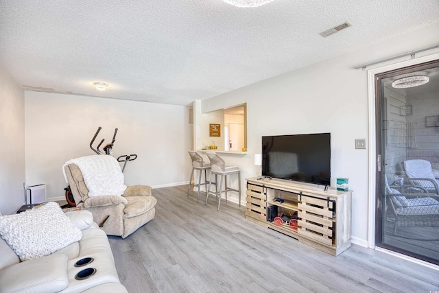 living area featuring a textured ceiling, visible vents, and wood finished floors