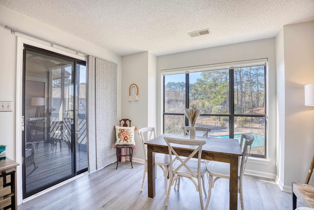 dining space featuring wood finished floors, visible vents, and baseboards