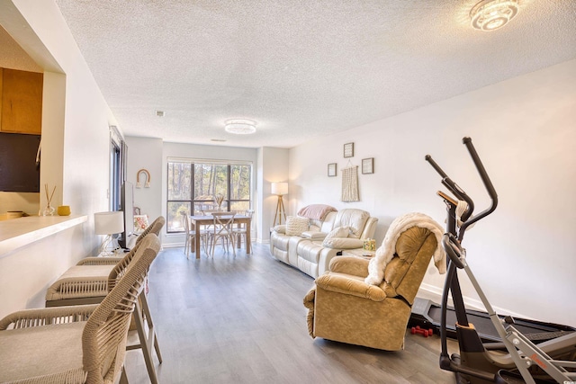 living room featuring a textured ceiling, a baseboard heating unit, wood finished floors, and baseboards