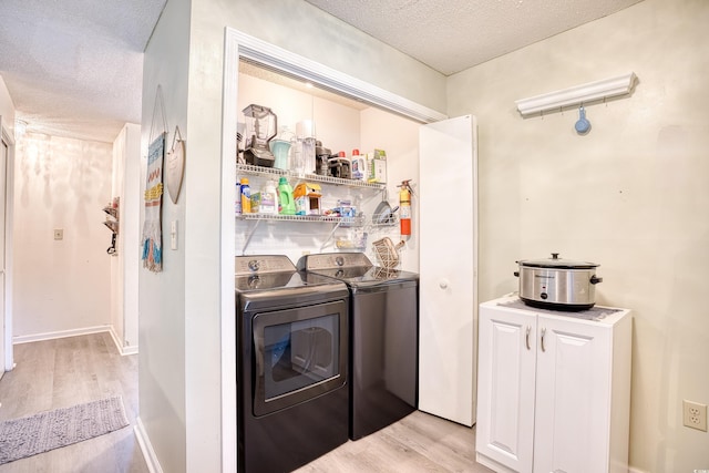 washroom with washing machine and dryer, a textured ceiling, and light wood finished floors