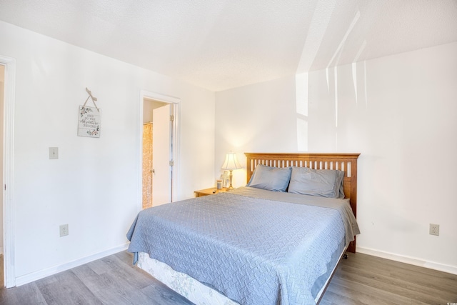 bedroom featuring a textured ceiling, baseboards, and wood finished floors