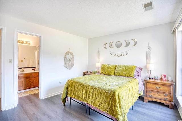 bedroom with a textured ceiling, wood finished floors, and visible vents