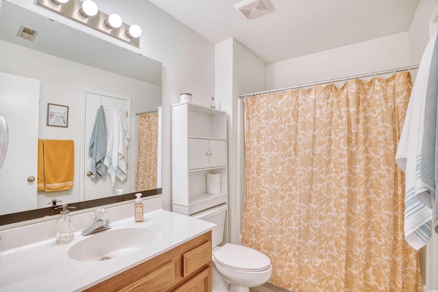 full bathroom featuring toilet, visible vents, a textured ceiling, and vanity