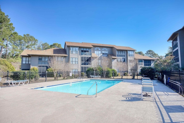 community pool with a patio area and fence