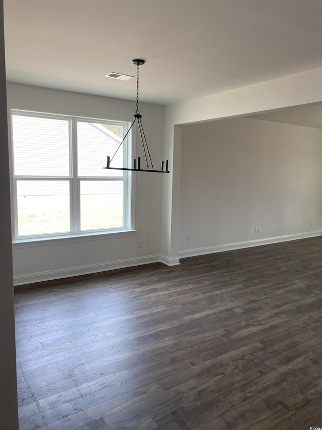 unfurnished dining area featuring a chandelier, dark wood-style floors, and baseboards