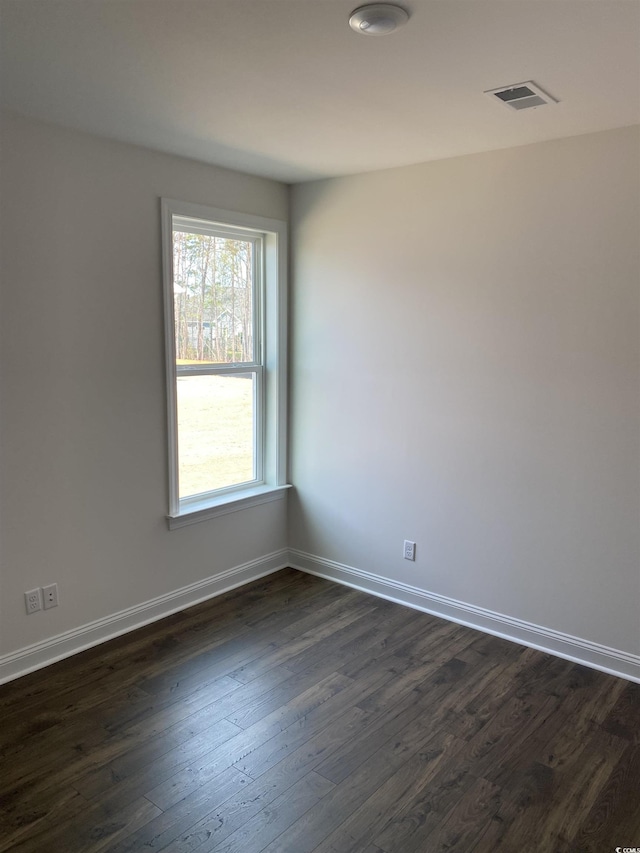 spare room featuring dark wood finished floors and baseboards