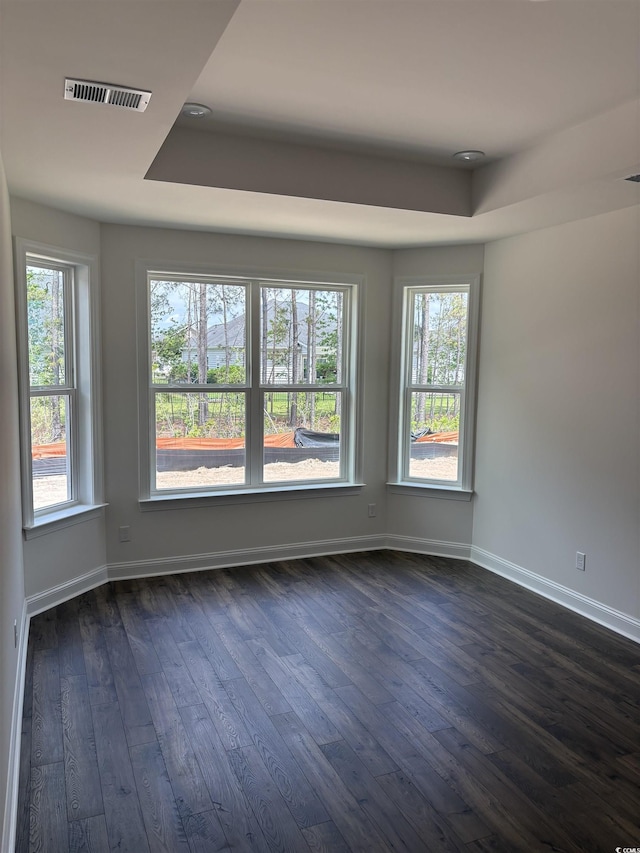 unfurnished room featuring dark wood-style floors, a raised ceiling, and baseboards