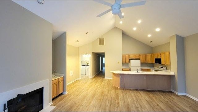 kitchen featuring decorative light fixtures, stove, ceiling fan, kitchen peninsula, and light hardwood / wood-style flooring