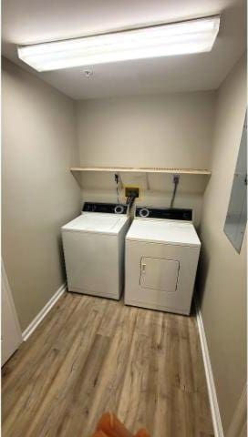 laundry room with light hardwood / wood-style floors, washer and dryer, and electric panel