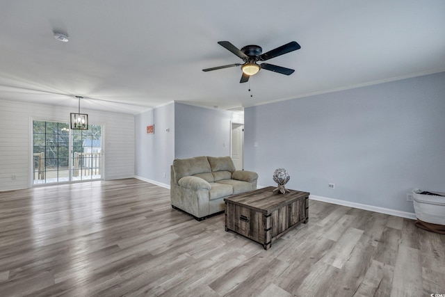 living room with crown molding, baseboards, and wood finished floors