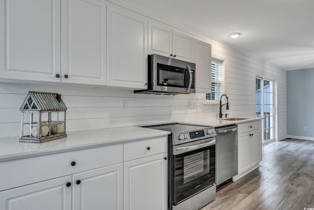 kitchen featuring stainless steel appliances, a sink, light wood-style flooring, and white cabinets