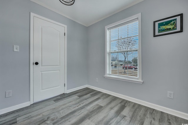 spare room featuring baseboards, ornamental molding, and wood finished floors