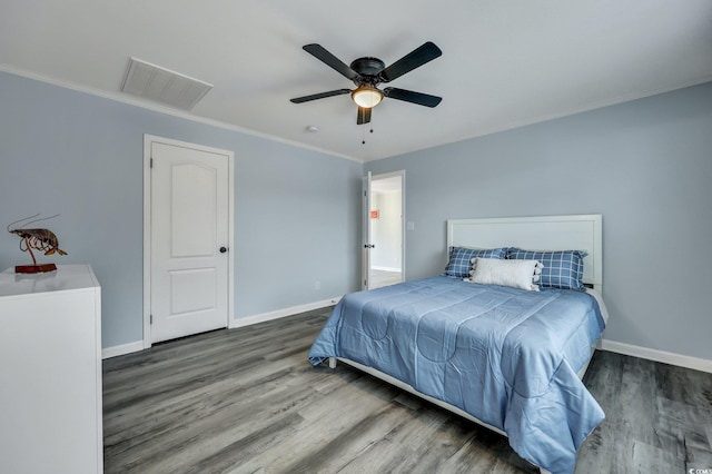 bedroom featuring ornamental molding, visible vents, baseboards, and wood finished floors