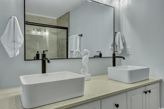 bathroom with double vanity, a shower stall, ornamental molding, and a sink