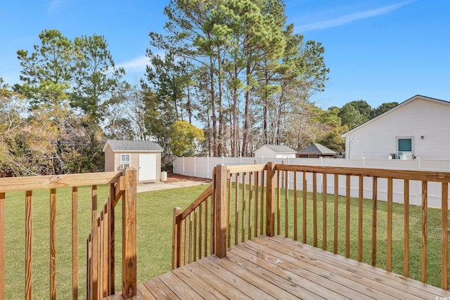 wooden terrace featuring a fenced backyard, a storage unit, a lawn, and an outdoor structure