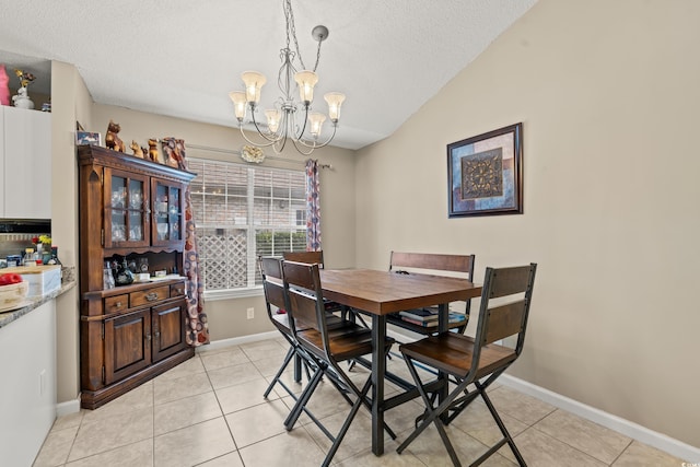 tiled dining area with a textured ceiling, lofted ceiling, and a notable chandelier