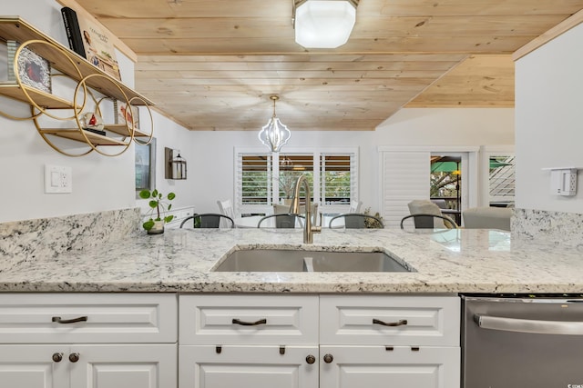 kitchen with light stone countertops, stainless steel dishwasher, and white cabinets