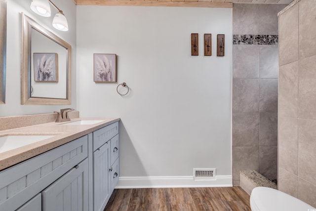 bathroom with vanity, tiled shower, hardwood / wood-style floors, and toilet