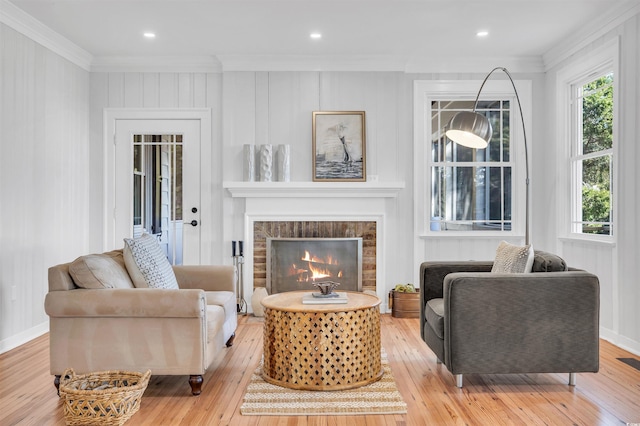 living room with ornamental molding, visible vents, a fireplace, and light wood finished floors