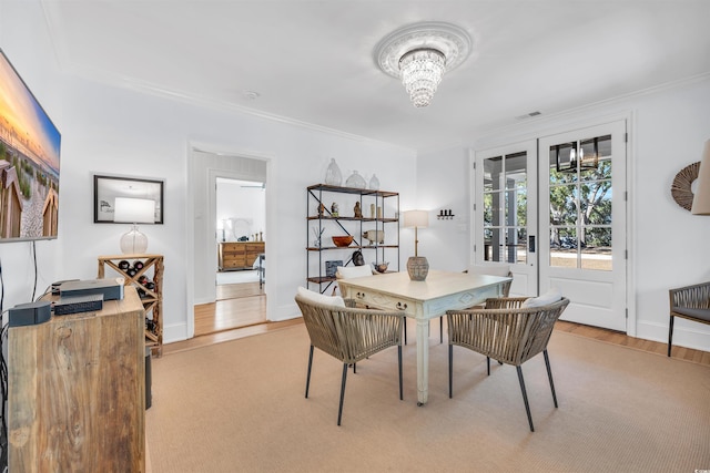 dining room with light wood finished floors, baseboards, ornamental molding, and a notable chandelier