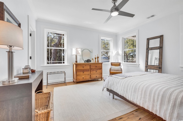 bedroom featuring light wood-style flooring, visible vents, and ornamental molding