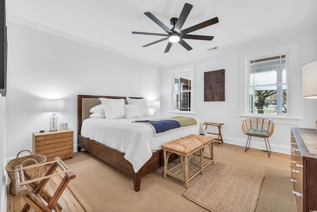 bedroom with light wood finished floors, baseboards, visible vents, and ornamental molding