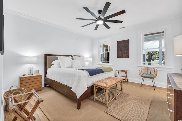bedroom with light wood-type flooring, baseboards, visible vents, and crown molding