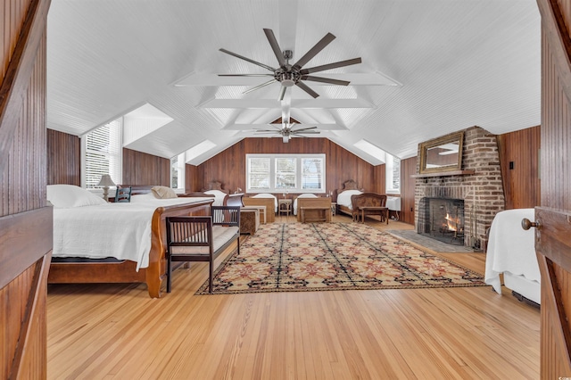 bedroom featuring vaulted ceiling, light wood-style flooring, and wooden walls