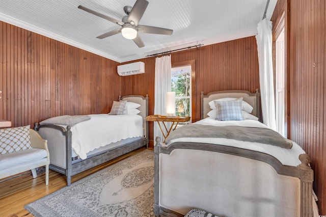 bedroom featuring crown molding, wooden walls, wood finished floors, and a wall mounted air conditioner