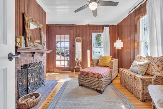 living area with crown molding, a fireplace, wooden walls, and light wood finished floors