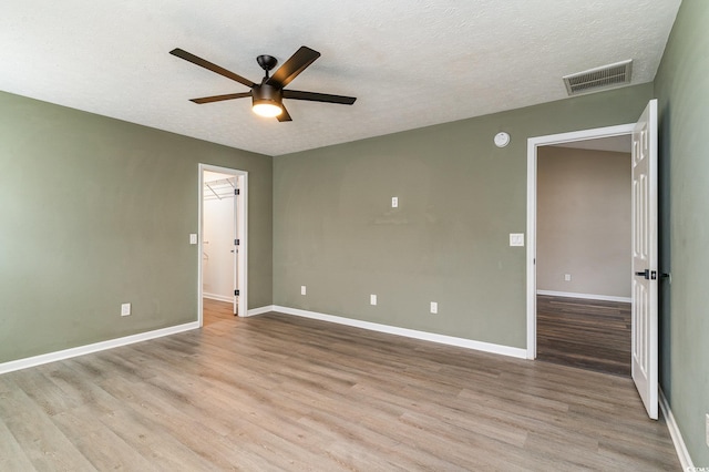 unfurnished room with ceiling fan, light hardwood / wood-style floors, and a textured ceiling