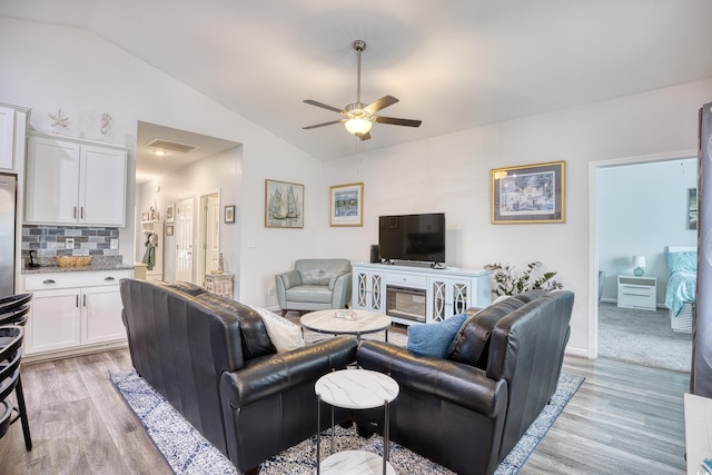 living room with lofted ceiling, ceiling fan, and light wood-type flooring