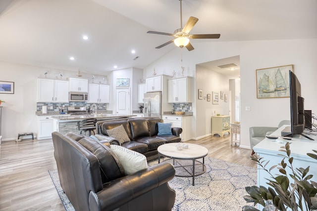 living room featuring vaulted ceiling, ceiling fan, and light hardwood / wood-style floors