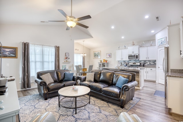 living room with lofted ceiling, ceiling fan with notable chandelier, and light hardwood / wood-style flooring