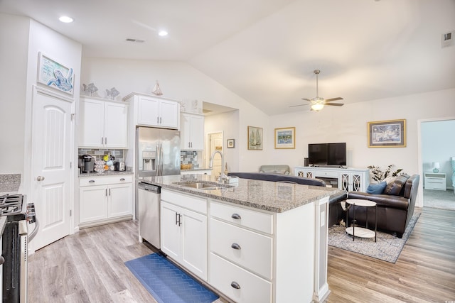 kitchen with sink, white cabinetry, stainless steel appliances, light stone counters, and an island with sink