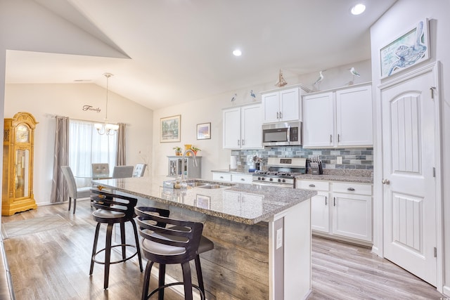 kitchen with sink, a breakfast bar area, white cabinetry, appliances with stainless steel finishes, and an island with sink