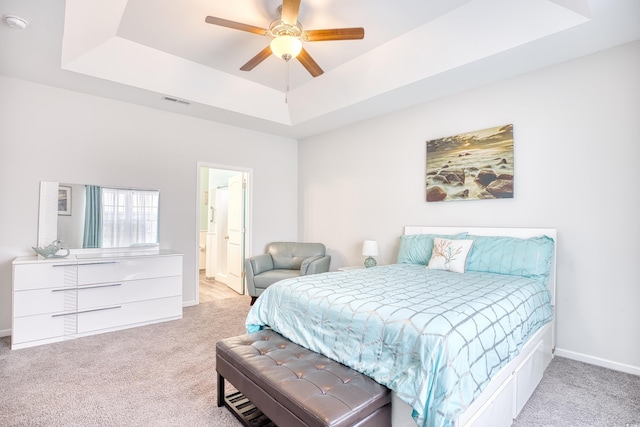 carpeted bedroom featuring ceiling fan, connected bathroom, and a raised ceiling