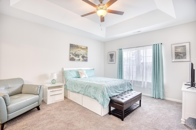 bedroom with ceiling fan, carpet flooring, and a tray ceiling