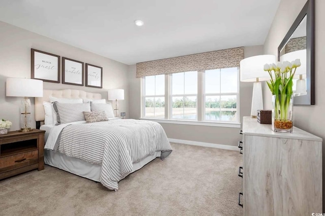 bedroom with carpet, a water view, and baseboards