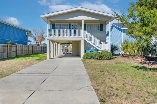 raised beach house featuring a front yard, a carport, and a porch