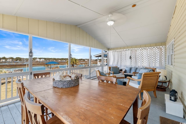 sunroom / solarium with a water view, vaulted ceiling, and ceiling fan