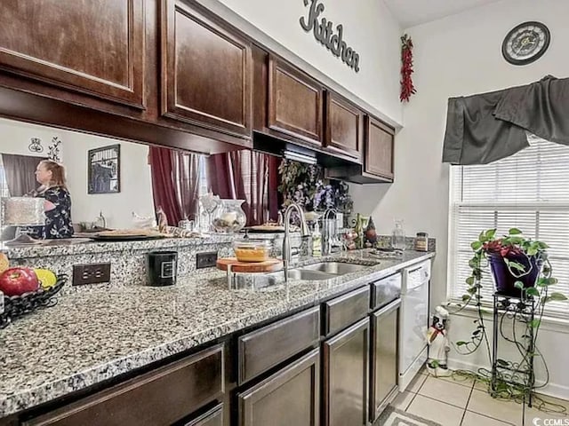 kitchen with light tile patterned flooring, dishwasher, sink, light stone counters, and dark brown cabinetry