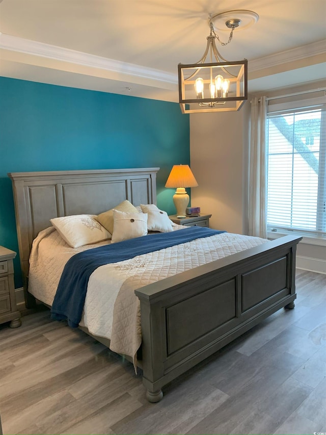 bedroom featuring hardwood / wood-style flooring, crown molding, and a chandelier