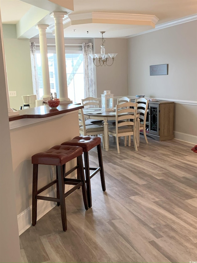 dining space featuring hardwood / wood-style flooring, crown molding, and ornate columns