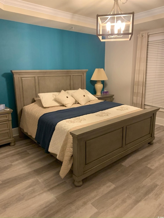 bedroom with light wood-type flooring, crown molding, and an inviting chandelier