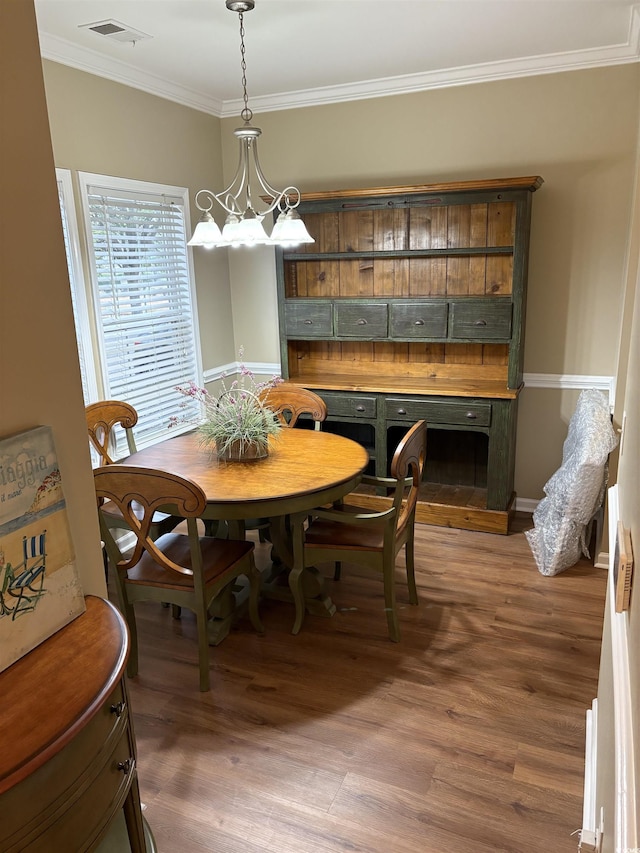 dining room featuring an inviting chandelier, crown molding, and dark hardwood / wood-style floors