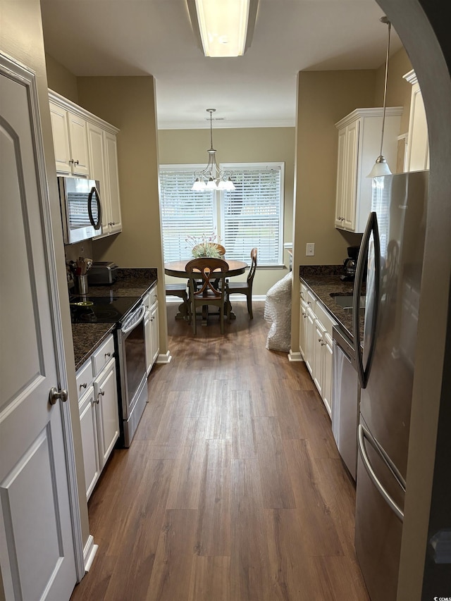 kitchen featuring appliances with stainless steel finishes, pendant lighting, white cabinets, and dark hardwood / wood-style flooring