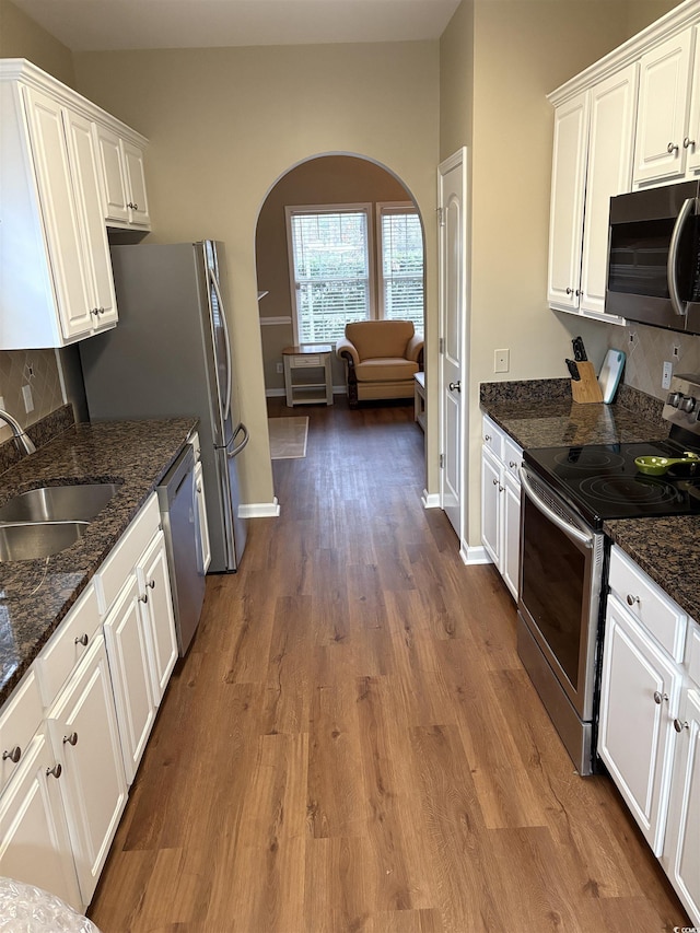 kitchen featuring stainless steel appliances, sink, dark stone counters, and white cabinets