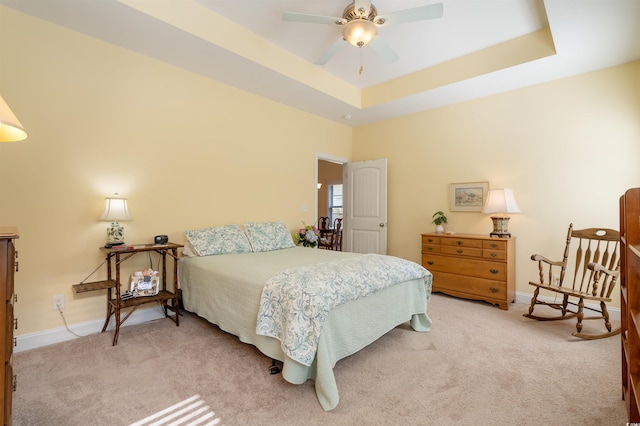 carpeted bedroom featuring a raised ceiling and ceiling fan