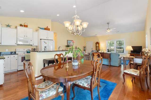 dining area featuring vaulted ceiling, wood-type flooring, and ceiling fan with notable chandelier